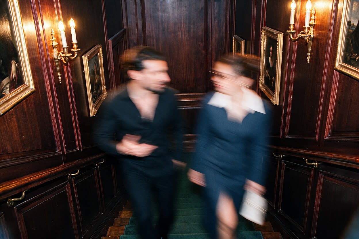 Couple en tenue de soirée dans l’escalier d’un club privé, univers Majellan